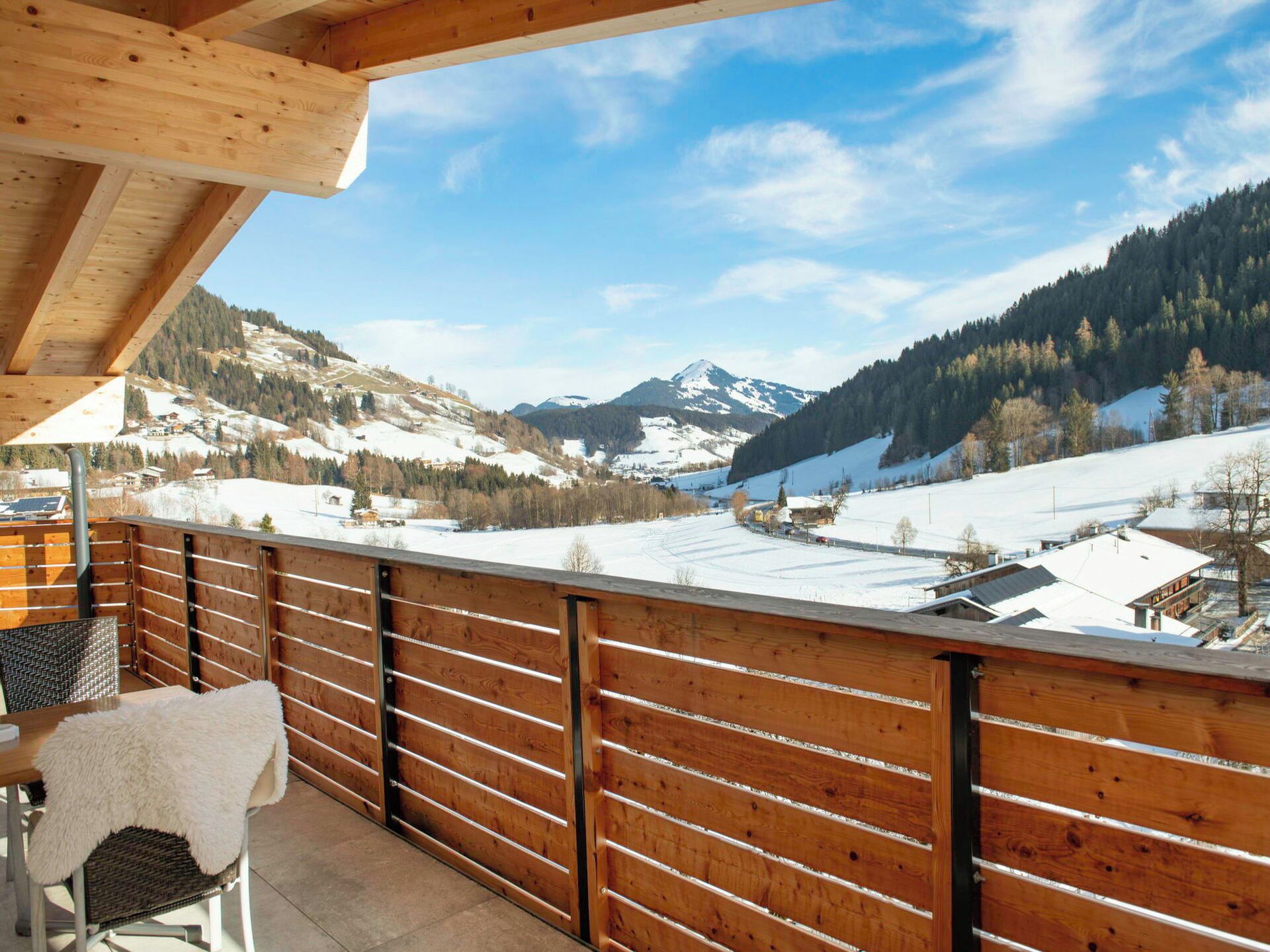 A wooden balcony with a view of a snowy mountain landscape.