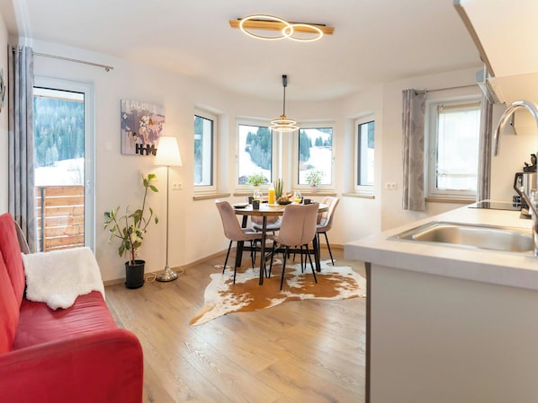 Eine moderne Küche mit Essbereich, Holzboden und großen Fenstern.