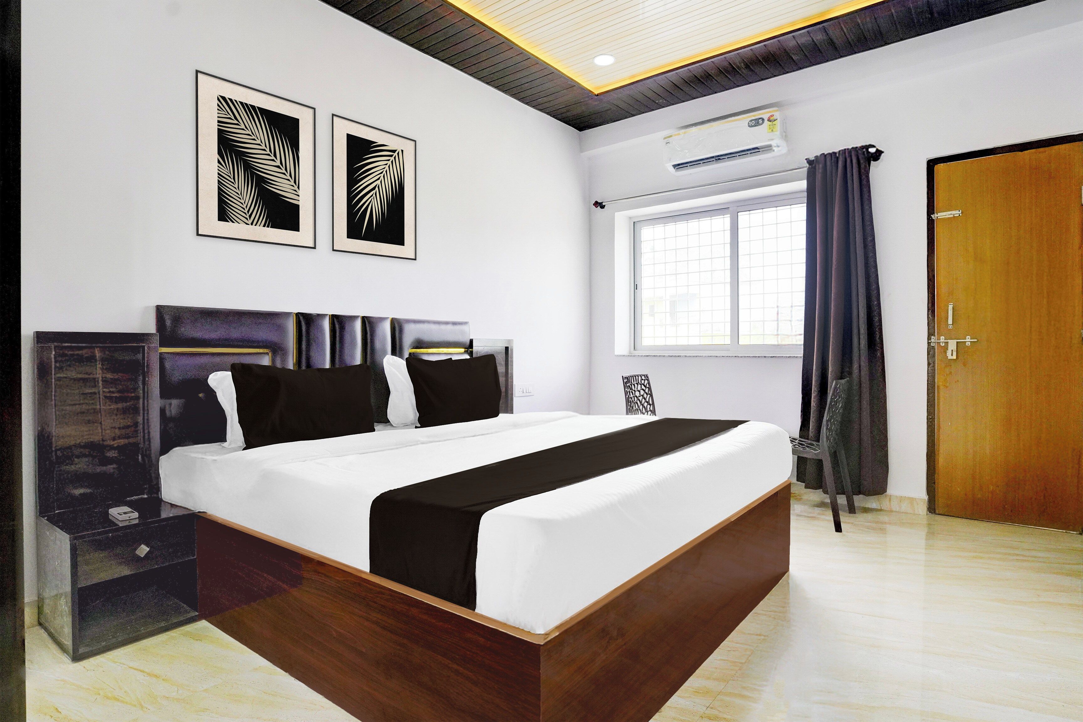 A modern bedroom with a large bed, a wardrobe, a window with curtains, and two wall-mounted artworks.
