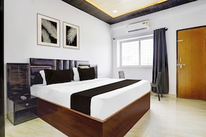 Un dormitorio moderno con una cama grande, un armario, una ventana con cortinas y dos obras de arte colgadas en la pared.