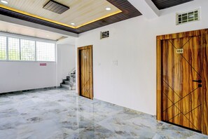 A hallway with marble flooring, wooden doors, and a staircase. - HOTEL O ROYAL INN (Nagpur)