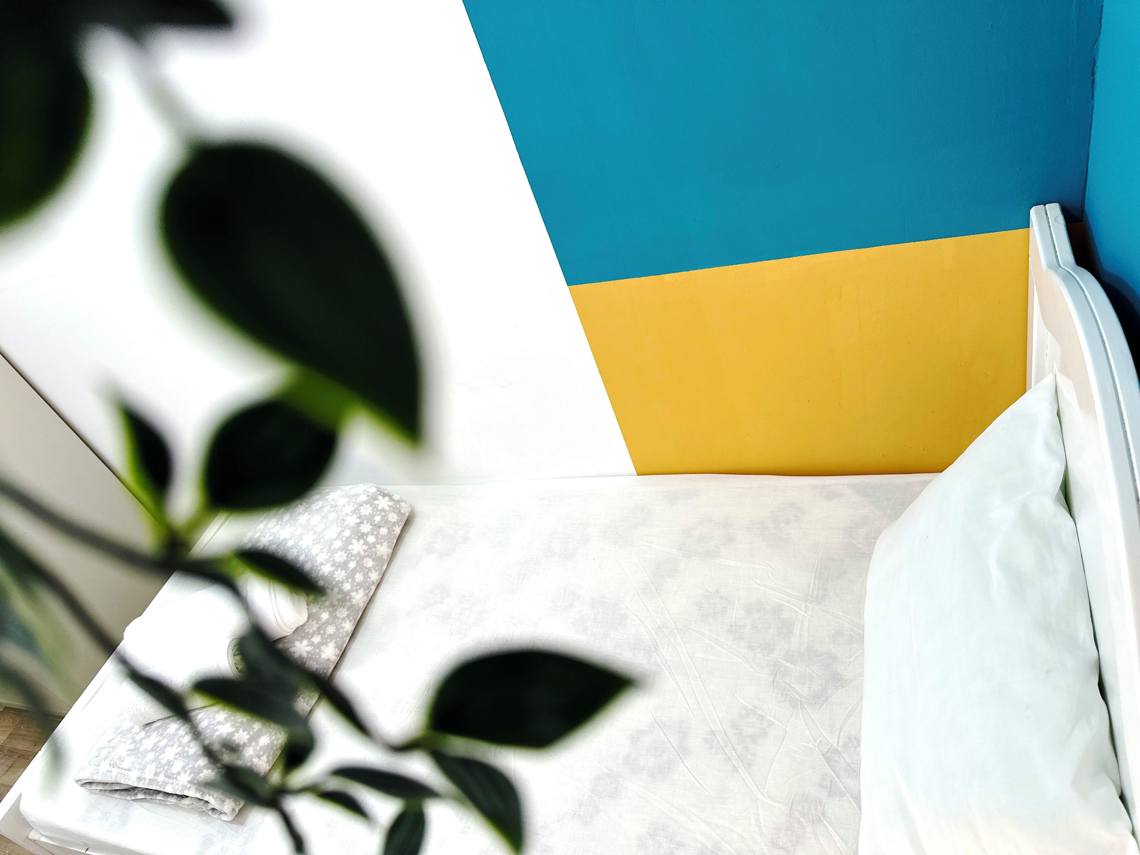 Een bed met een witte matras, een kussen en een deken met een bloemenpatroon.