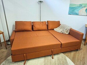 A sectional sofa with a blanket, a floor lamp, and a painting on the wall. - Cosy apartment for 4 people with WIFI, TV, patio, pets allowed and panoramic view (Weißenbach)