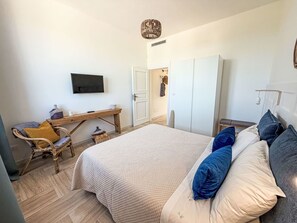 Ein Schlafzimmer mit einem Bett, einem Schreibtisch, einem Stuhl, einem Kleiderschrank und einem Fernseher.