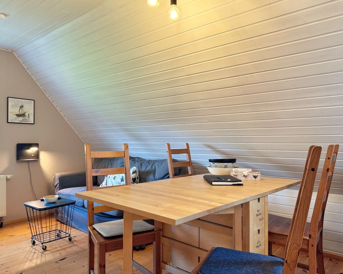 A cozy room with a wooden dining table, chairs, a sofa, and a TV.