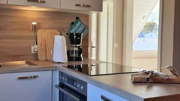 A modern kitchen with a built-in oven, a coffee maker, and a wooden countertop.