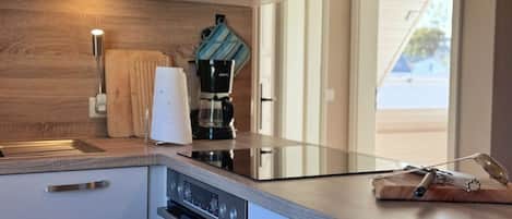 A modern kitchen with a built-in oven, a coffee maker, and a wooden countertop.