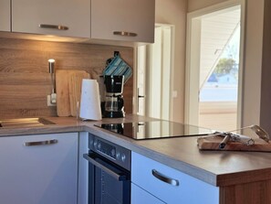 A modern kitchen with a built-in oven, a coffee maker, and a wooden countertop. - Vrbo Property (Polchow)