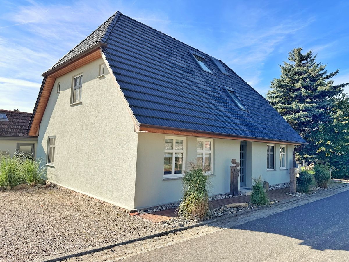 A single-story house with a sloped roof, a visible window, and a small porch area.