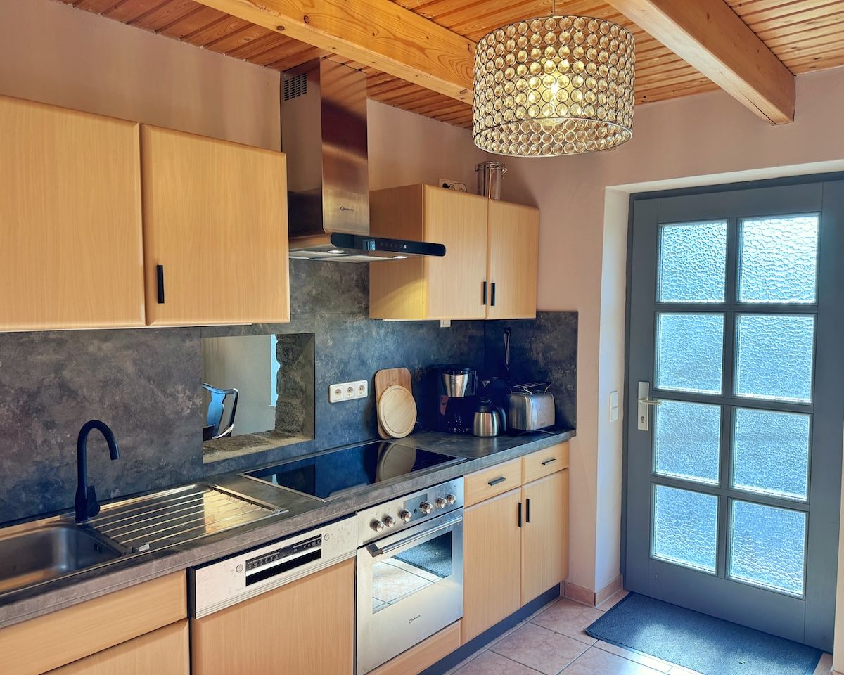 Une cuisine moderne avec des meubles en bois, un four encastré et une grande fenêtre.