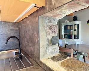 A modern kitchen with a built-in sink, a stone accent wall, and a dining area with a table and chairs. - Vrbo Property (Polchow)