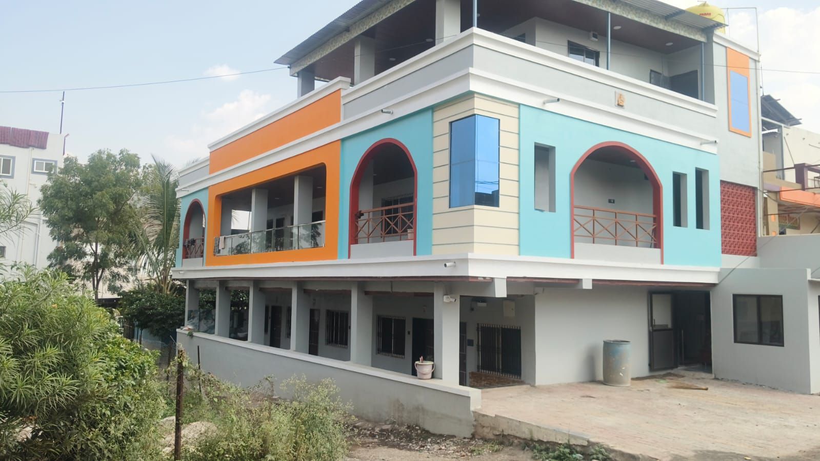 A multi-story building with a flat roof, balconies, and a gated entrance.