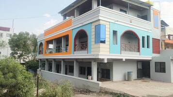 A multi-story building with a flat roof, balconies, and a gated entrance.