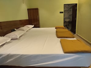 Una cama individual con ropa de cama blanca y mostaza, cabecero de madera y un armario de madera pequeño.