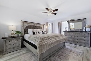 Quarto com cama grande, penteadeira, espelho e ventilador de teto.