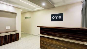 Un área de recepción con un mostrador de madera, un ventilador de techo y un letrero que dice 'OYO'.