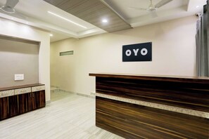 Un área de recepción con un mostrador de madera, un ventilador de techo y un letrero que dice 'OYO'.