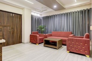 A living room with a sofa set, a coffee table, and a wooden door. - Hotel O Luxe Villa (Nagpur)
