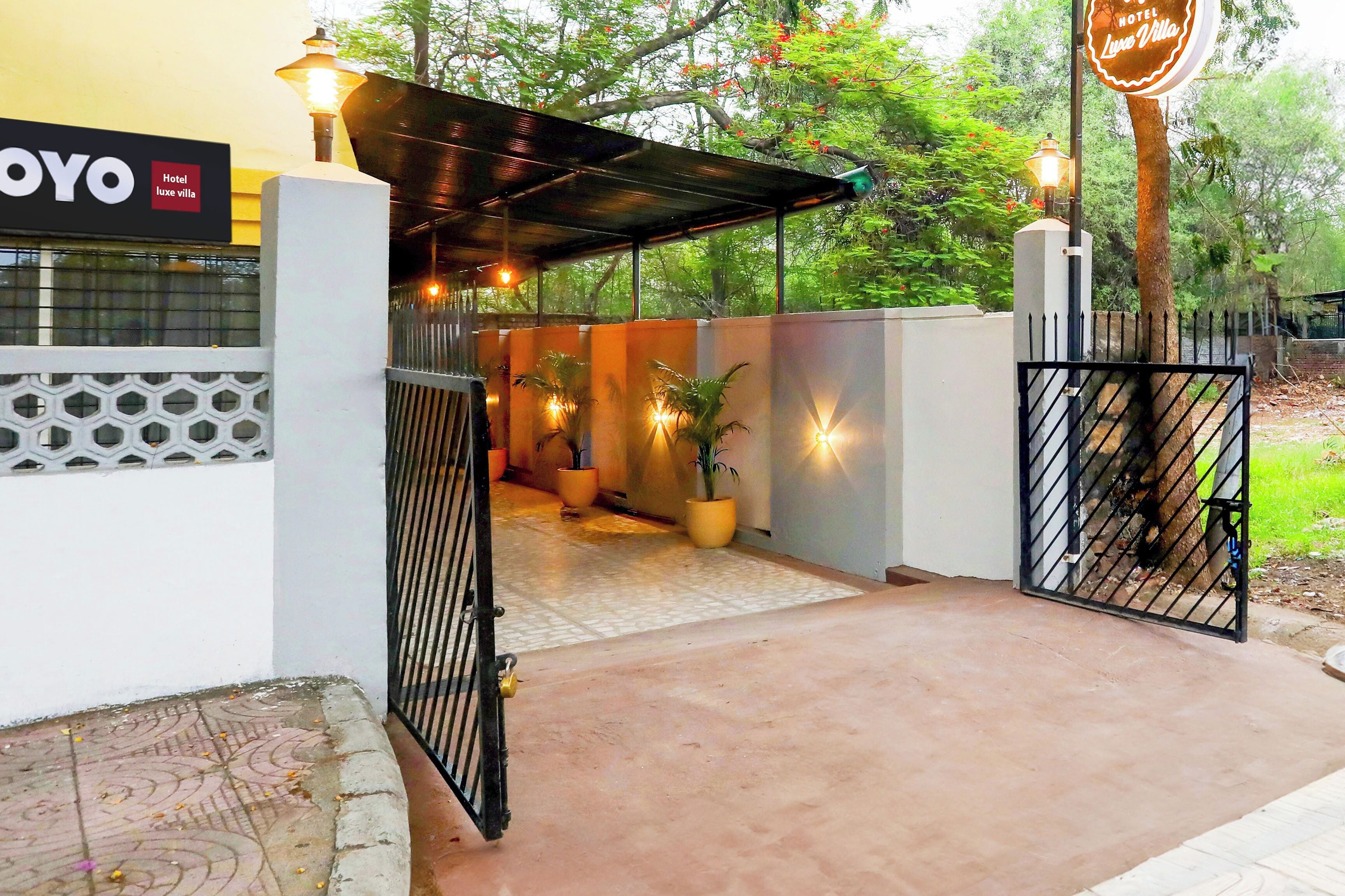 A hotel entrance with a covered walkway, potted plants, and a sign for 'Hotel Luxe Villa.'