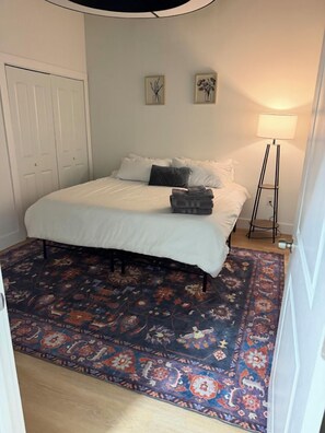 A bedroom with a bed, a standing lamp, and a patterned rug. - Close to what brought you here. Comfortable enough to make coming back the best part. (Montgomery)