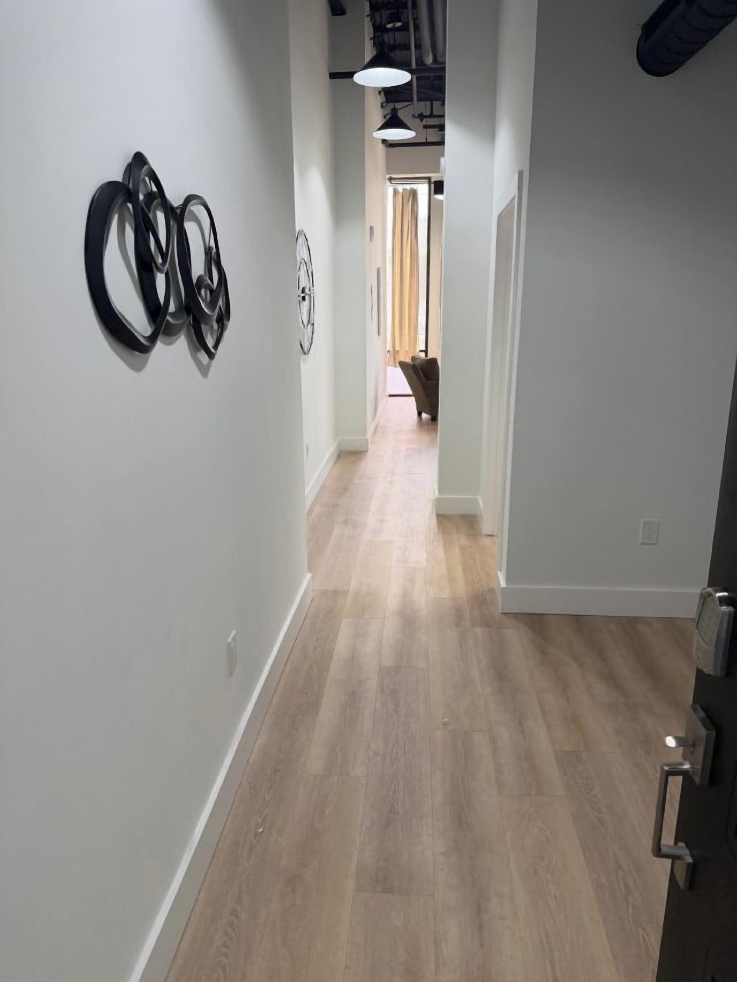 A hallway with a wooden floor, a door on the right, and wall-mounted circular decorations.