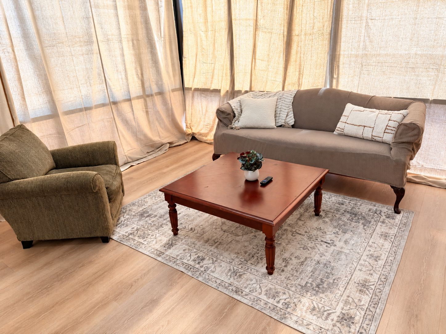Un salon comprenant un canapé, un fauteuil, une table basse et un tapis à motifs.