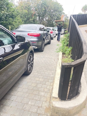 A paved driveway with parked cars and a wooden fence. - The Ridge London | Luxury Home (Belvedere)