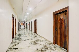 A long hallway with marble flooring and wooden doors, leading to a reception area at the end.