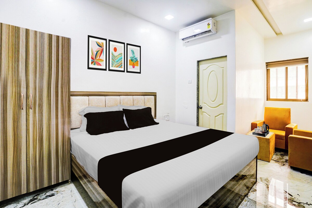 A hotel room with a bed, a wardrobe, a desk with a chair, and a door.