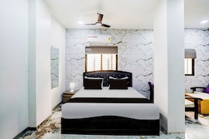 Een slaapkamer met een bed, een plafondventilator, een airconditioning, een raam en een bureau met een stoel.
