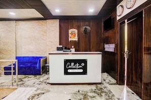 Een receptie met een marmeren vloer, een blauwe bank, een receptiebalie en een klok aan de muur.