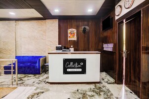 A reception area with a marble floor, a blue sofa, a reception desk, and a clock on the wall.