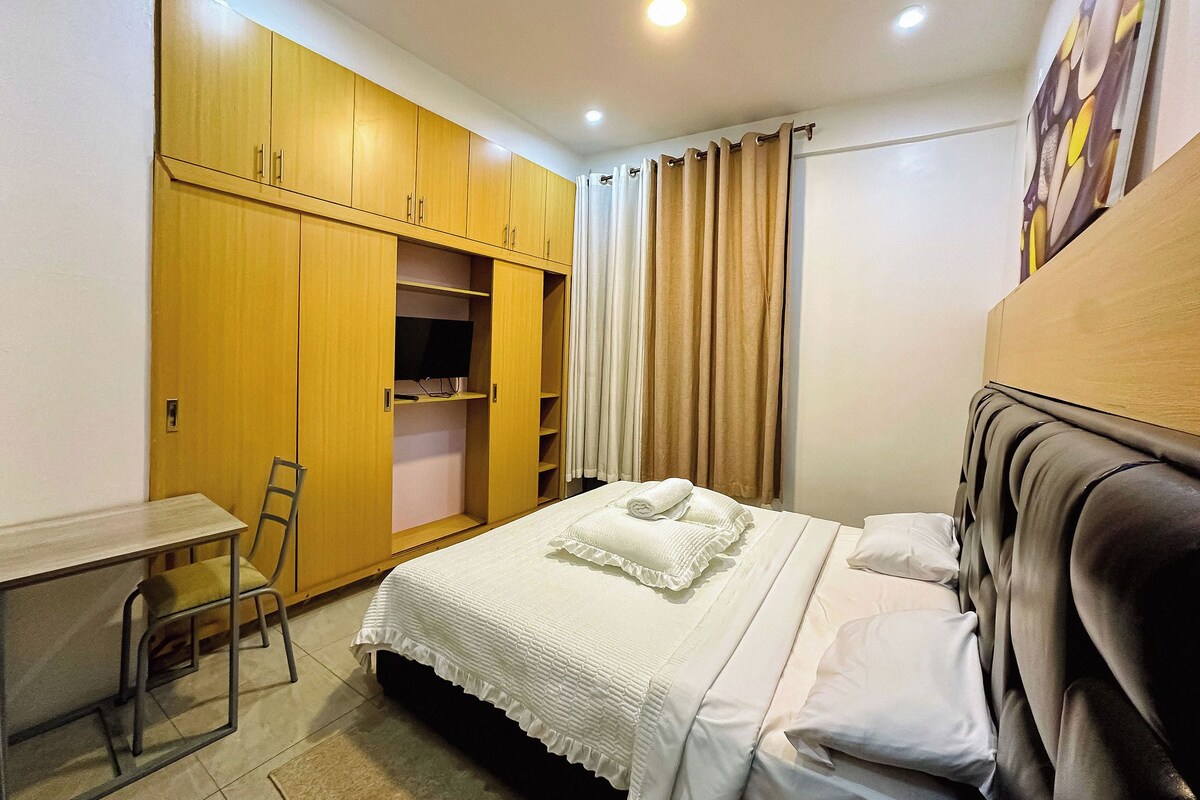 A bedroom with a bed, a desk, and a wardrobe.