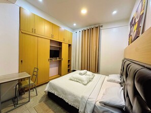 A bedroom with a bed, a desk, and a wardrobe. - Poolside View Guesthouse (Kigali)