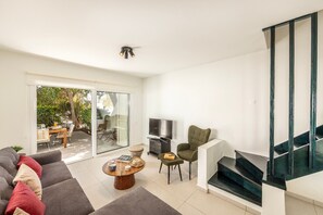 Un salon moderne avec un canapé gris, une table basse, un téléviseur et un escalier.