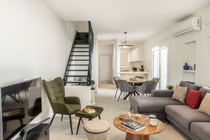 Un salon moderne doté d’un téléviseur à écran plat, d’un canapé, d’une table basse et d’un escalier menant à l’étage supérieur.