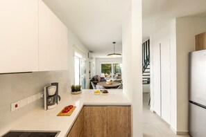 A modern kitchen with a central island, a coffee machine, and a dining area with a table and chairs. - 3 Bedroom Villa In The Heart of Protaras (Paralimni)