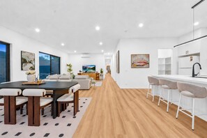 A modern interior with a dining area, kitchen, and living space. - 2 New Bayswater Homes | 8BR/6BA, Sleeps 16 (Bayswater)