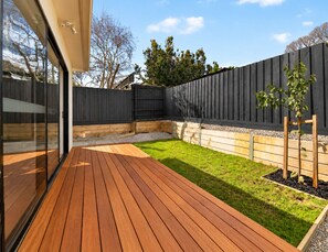 A wooden deck with a grassy area and a dark fence. - 2 New Bayswater Homes | 8BR/6BA, Sleeps 16 (Bayswater)
