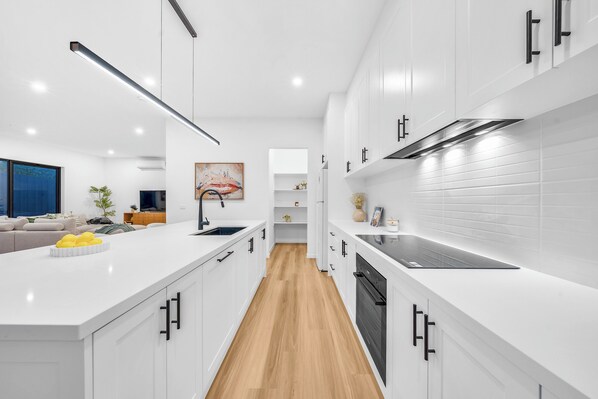 Een moderne keuken met witte kastjes, een centraal eiland en een houten vloer.