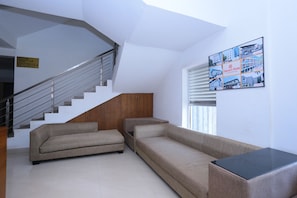 Un interior moderno con una escalera, un sofá y un anuncio en la pared.