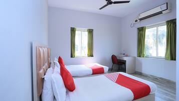 Habitación de hotel con dos camas, un escritorio, una silla, aire acondicionado y ventilador de techo.