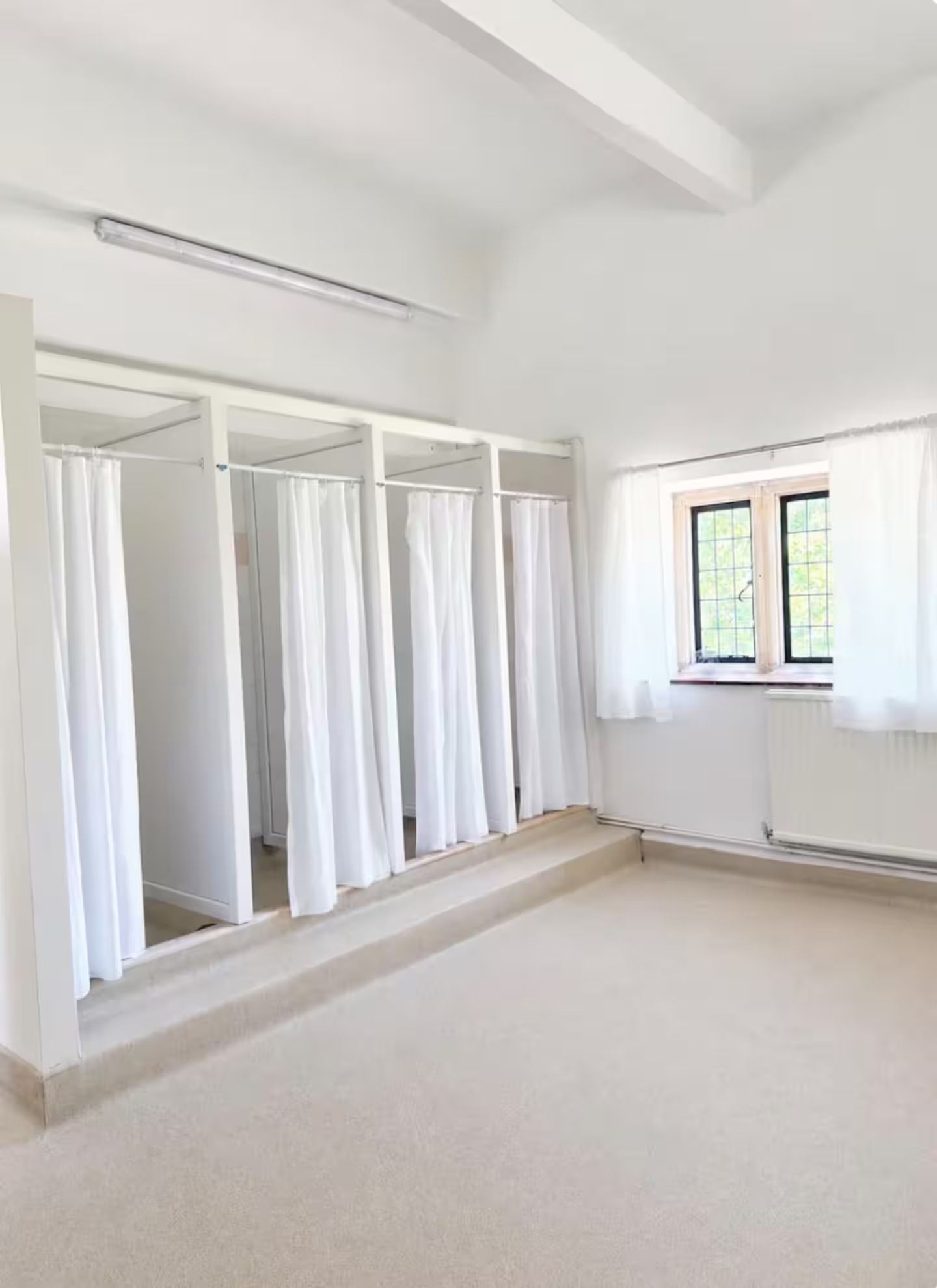 Una habitación con un ventanal grande, un armario empotrado con varias puertas y un piso cubierto de alfombra.