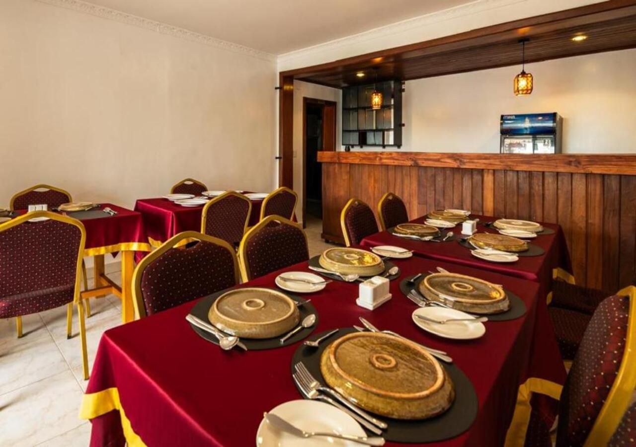 A dining area with tables set for service, chairs, and a bar area with a counter.