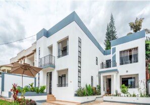 A modern two-story residential building with balconies, a covered patio, and a well-maintained garden. - Nzeli Hotel & Resort (Kigali)