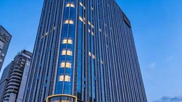 A modern high-rise building with a prominent glass facade and a curved lower section.