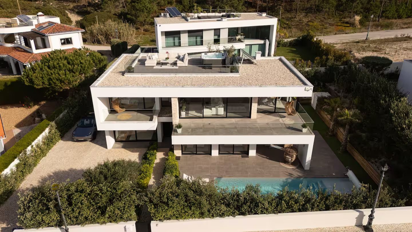 A modern two-story house with a rooftop pool, a hot tub, and a car parked in the driveway.