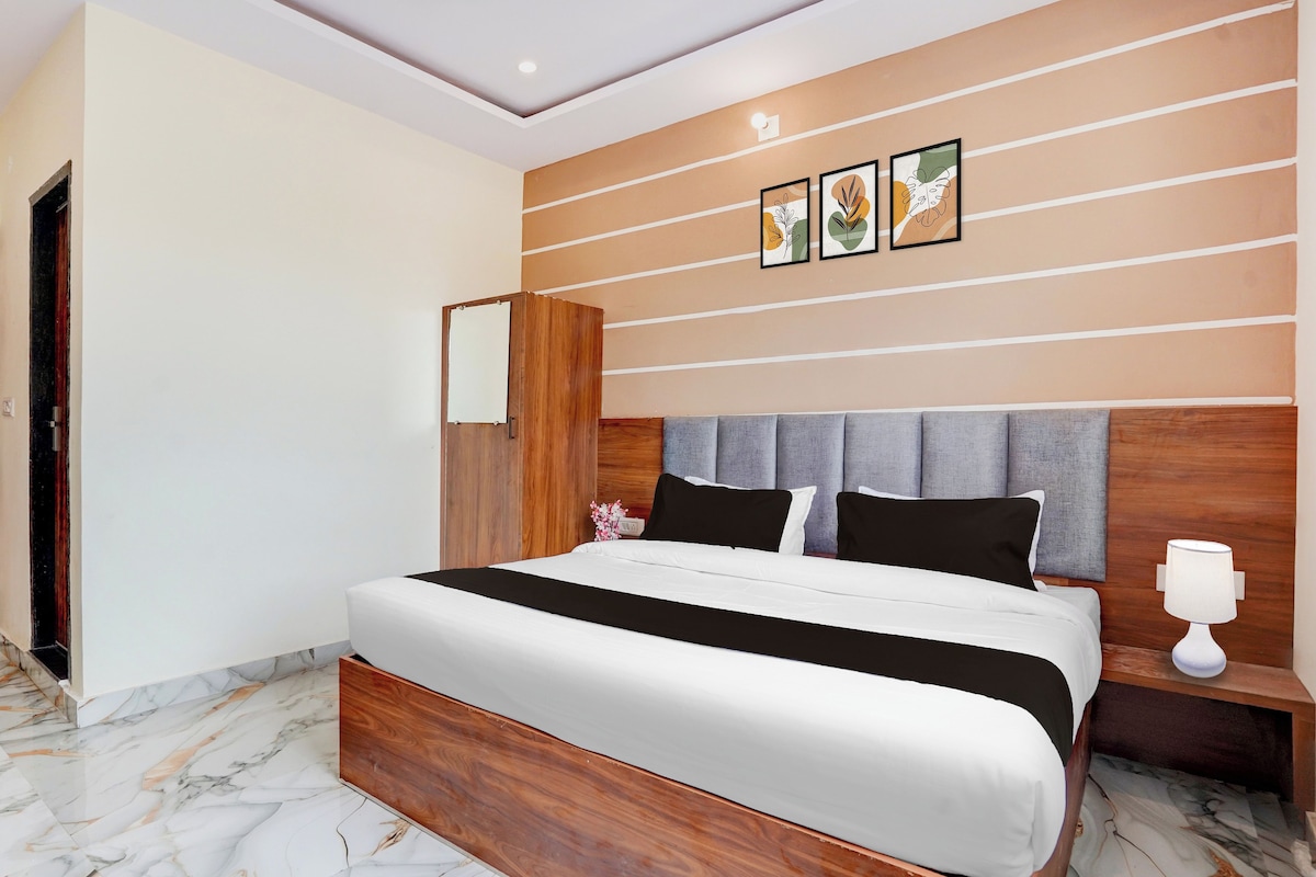 A modern bedroom with a large bed, a wooden headboard, and a nightstand with a lamp.