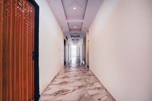 A hallway with a marble floor, a wooden door on the left, and a ceiling with recessed lighting. - Collection O Radha Krishna Vrindavan (Vrindavan)
