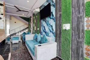 A modern hotel lobby with a marble wall, green artificial grass, a sofa with blue cushions, and a staircase. - Collection O Radha Krishna Vrindavan (Vrindavan)
